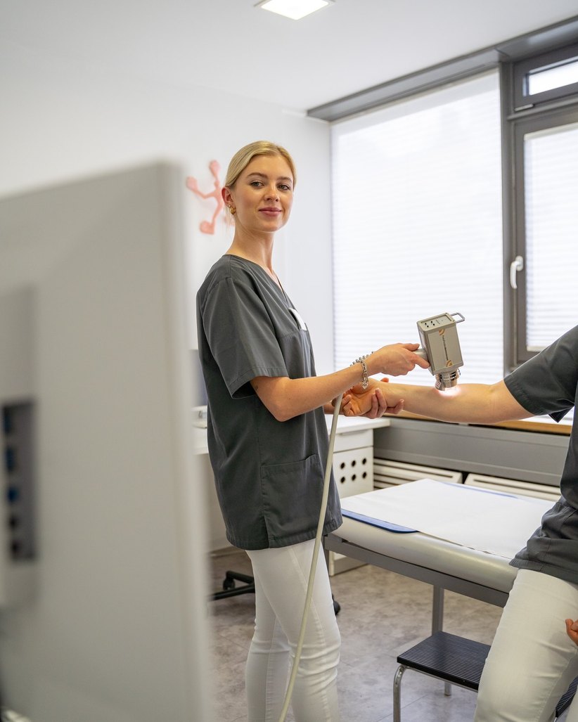 Mitarbeiterin mit dem Fotofinder-System am Arm eines Patienten